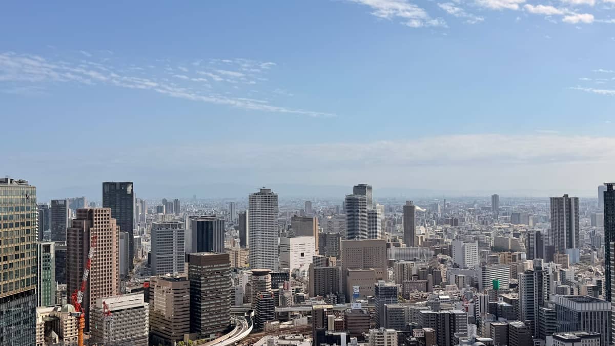 Panoramic view of Osaka's urban skyline under a clear blue winter sky, with high-rise buildings and no snow visible.