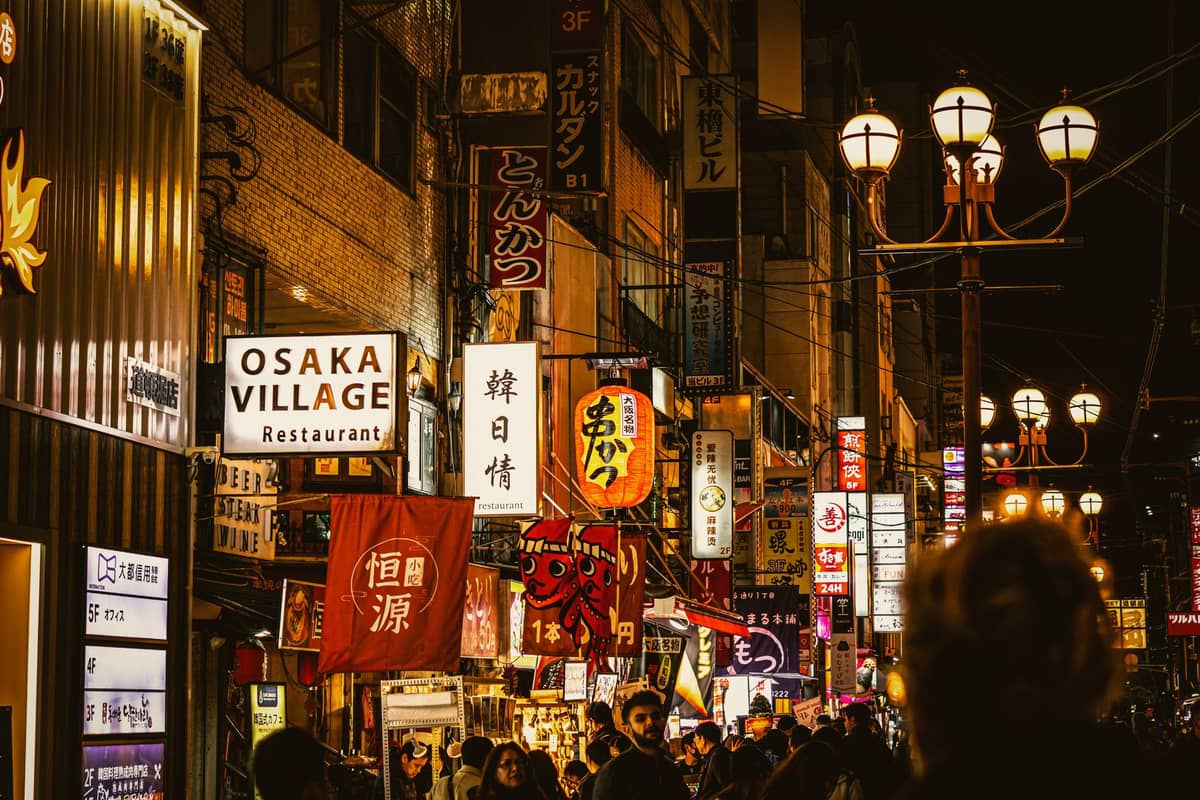 Night scene in Osaka with crowds, illuminated signs, and a vibrant street atmosphere near restaurants and nightlife spots.