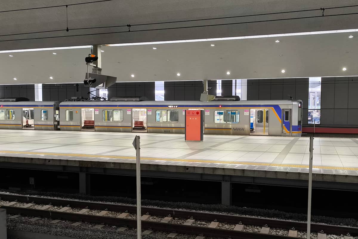 Nankai Railway train at Kansai International Airport station platform, modern interior, minimal passengers, wide tracks visible
