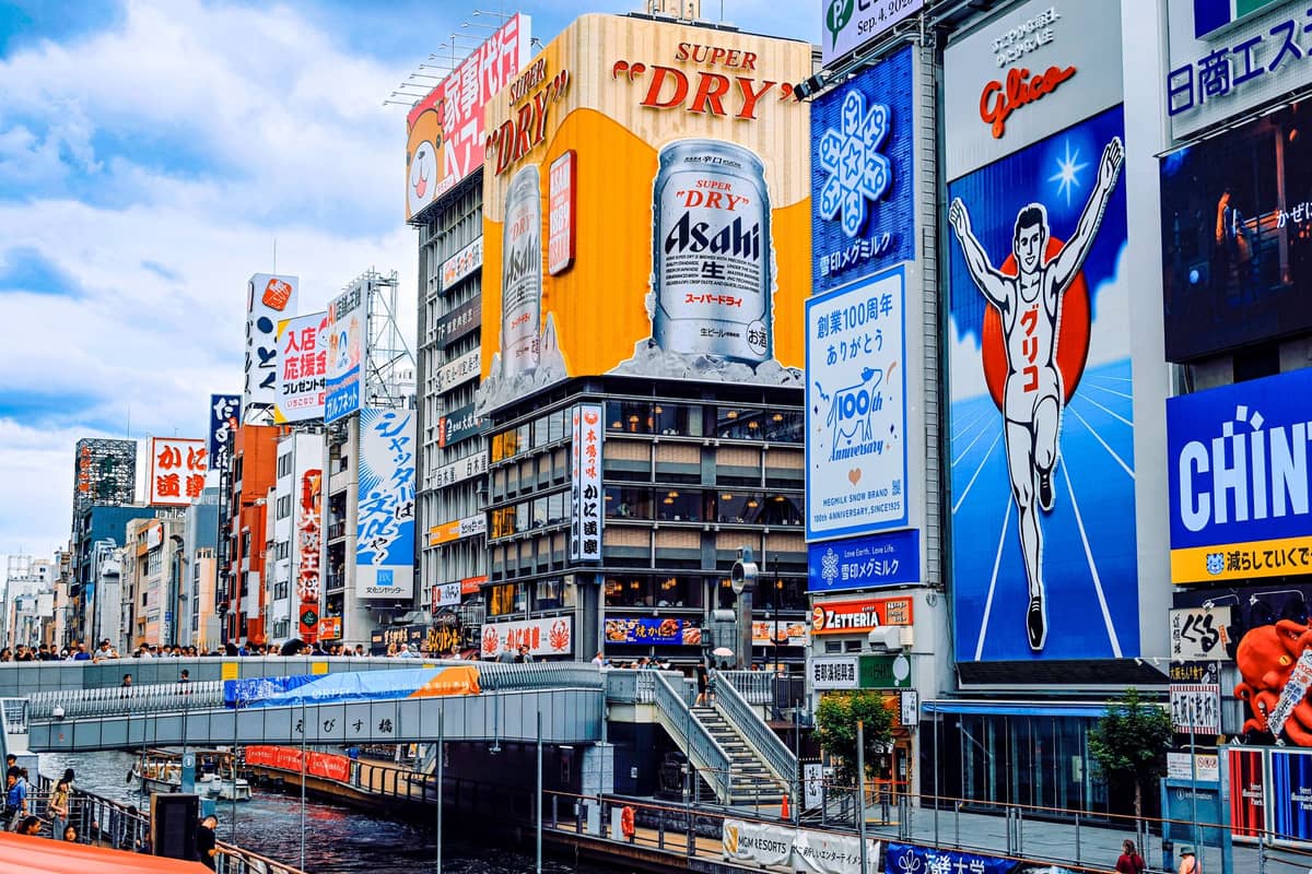 Crowds and a dazzling array of neon signs at Osaka’s Dotonbori shopping district, featuring the famous Glico running man billboard along the canal.