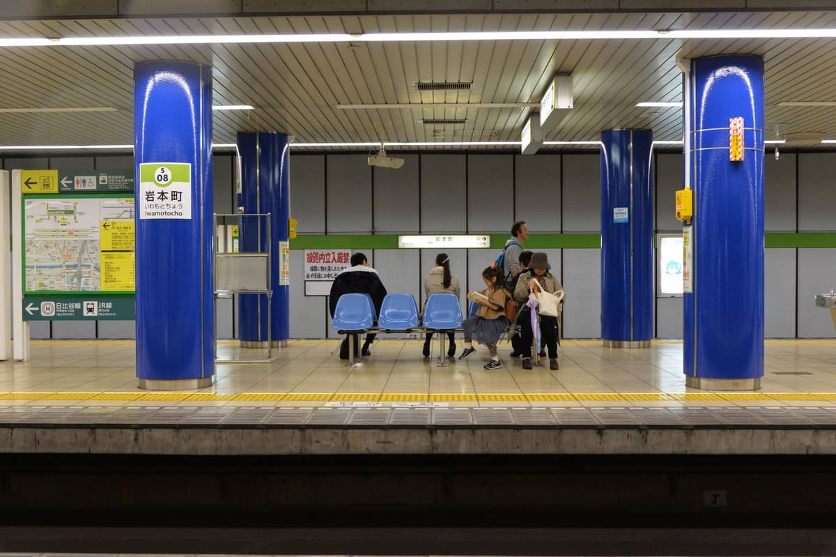 Family with children waiting at an Osaka Metro platform, surrounded by blue pillars and accessible signage.