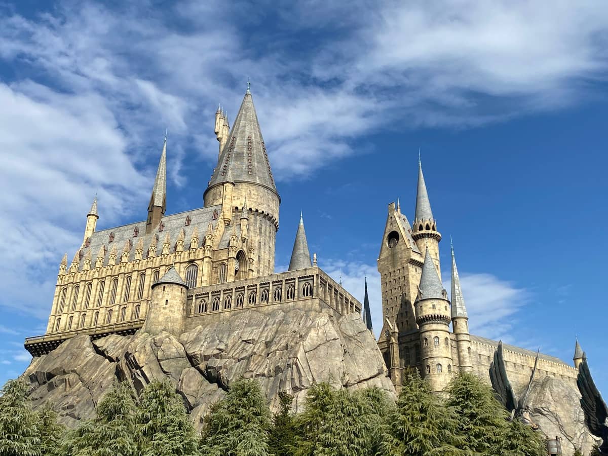 Hogwarts castle replica at Universal Studios Japan on a bright sunny day, surrounded by lush green trees.