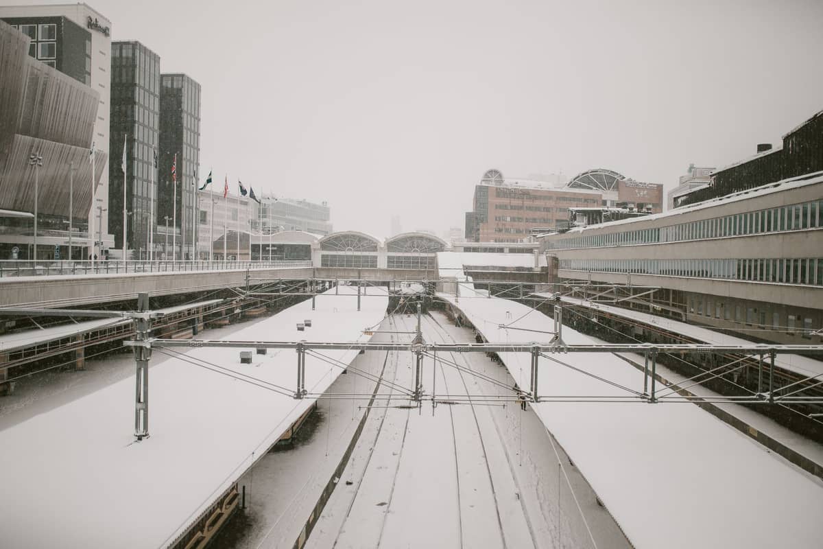 รางรถไฟและชานชาลาที่ปกคลุมด้วยหิมะที่ Oslo Sentralstasjon ล้อมรอบด้วยอาคารสมัยใหม่ในฤดูหนาว
