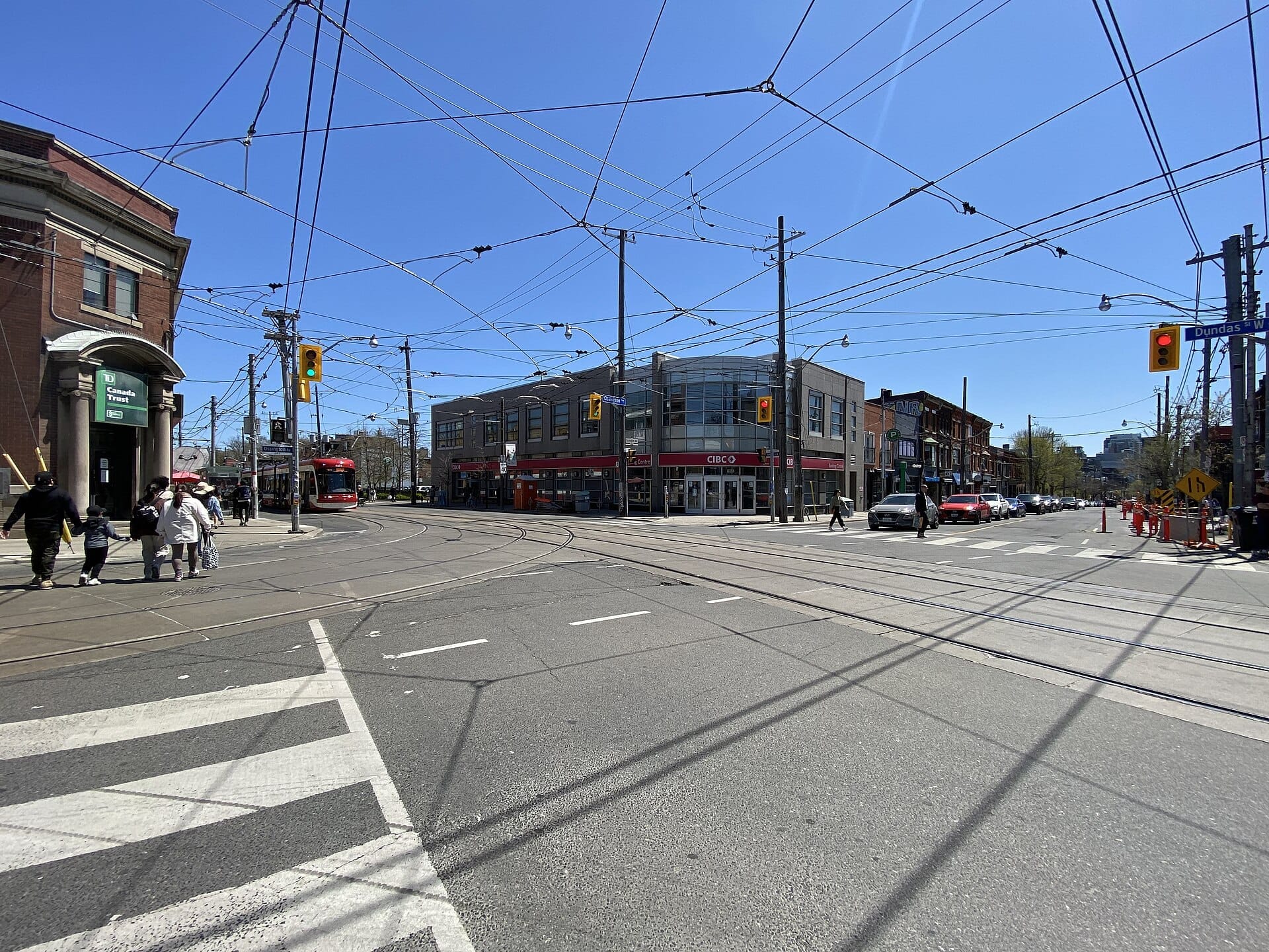 ทางแยกของ Ossington Avenue และ Dundas Street West ในโตรอนโต มีเส้นทางรถราง คนเดินถนน และอาคารที่ผสมผสานระหว่างประวัติศาสตร์และความทันสมัย