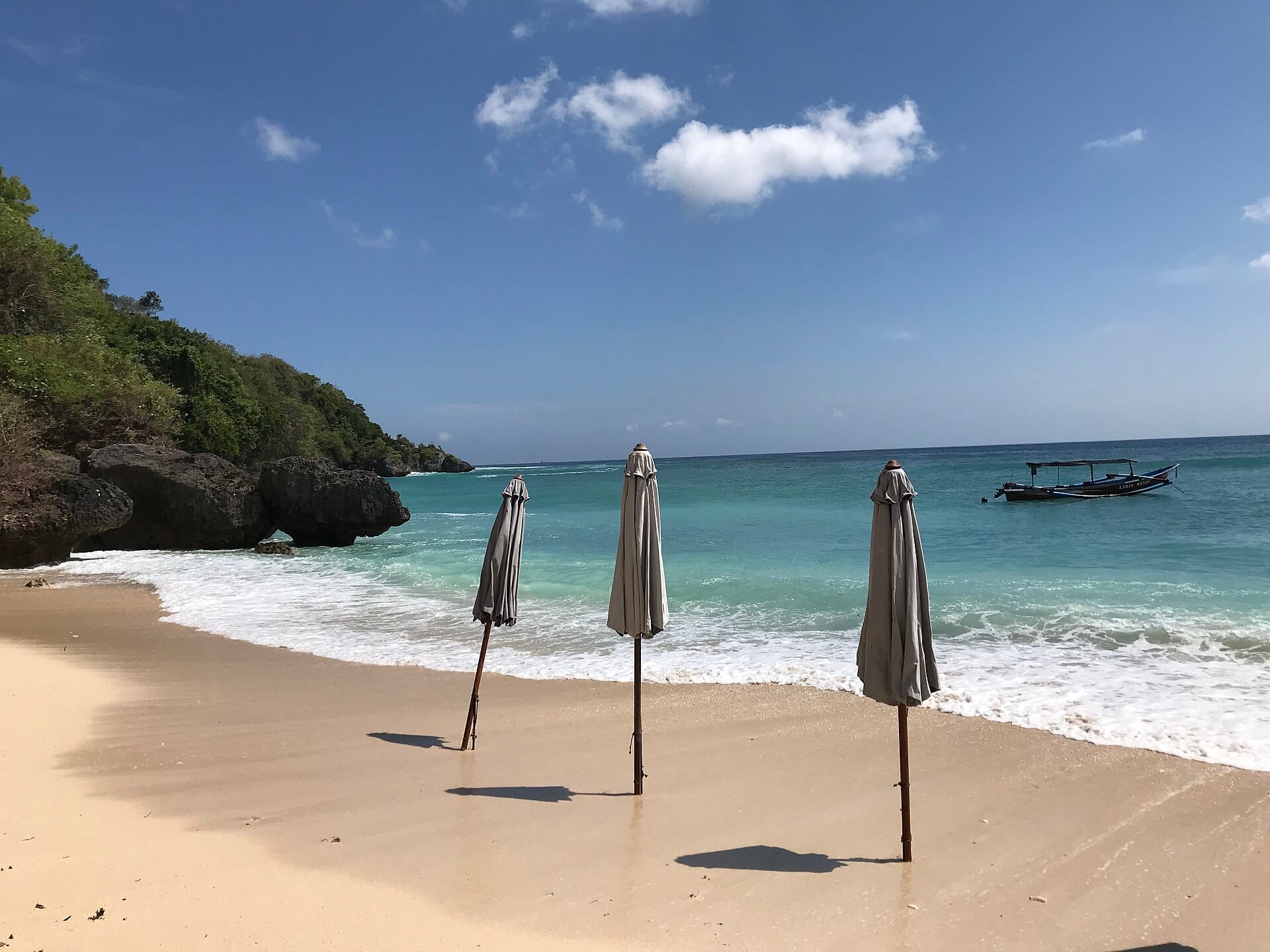 L'iconica spiaggia di Padang Padang a Bali con sabbia dorata, acque cristalline dell'Oceano Indiano e promontori rocciosi.