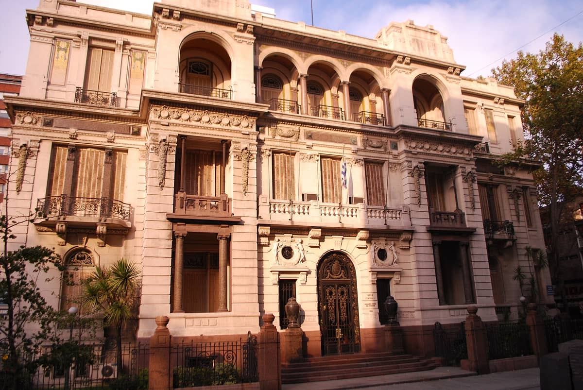 ด้านหน้าอาคาร Palacio Piria ในมอนเตวิเดโอ ตกแต่งระเบียง ลายปูนปั้น หน้าต่างโค้ง รับแสงอบอุ่นยามบ่าย