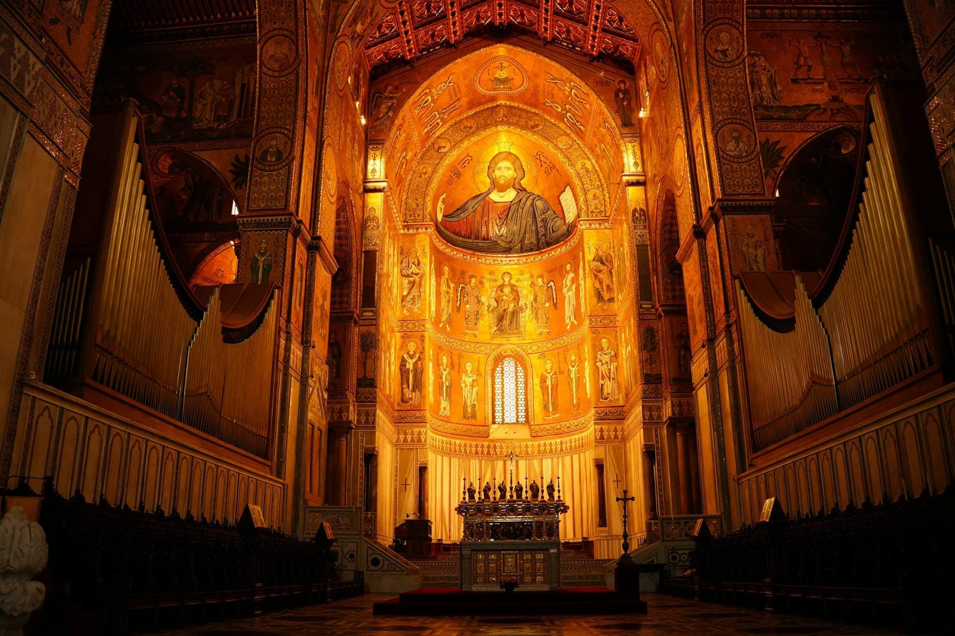 Weitwinkelansicht der goldenen byzantinischen Mosaiken, hohen Bögen und der reich verzierten Decke der Palatinischen Kapelle über dem Hauptaltar, in warmem Licht strahlend.