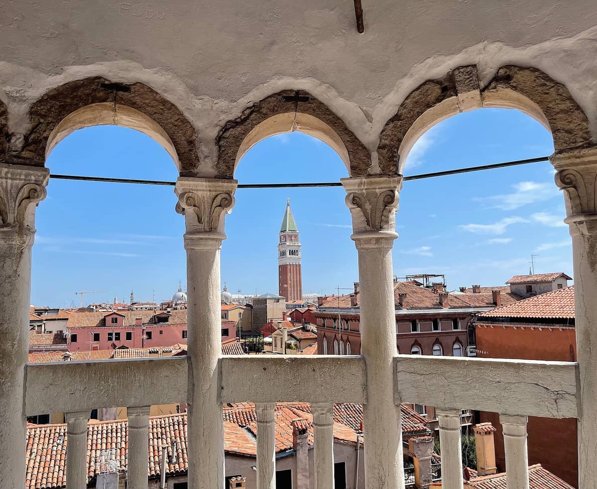 Blick von der Loggia der Wendeltreppe des Palazzo Contarini del Bovolo durch die Bogensäulen auf die Dächer Venedigs und den Campanile von San Marco.
