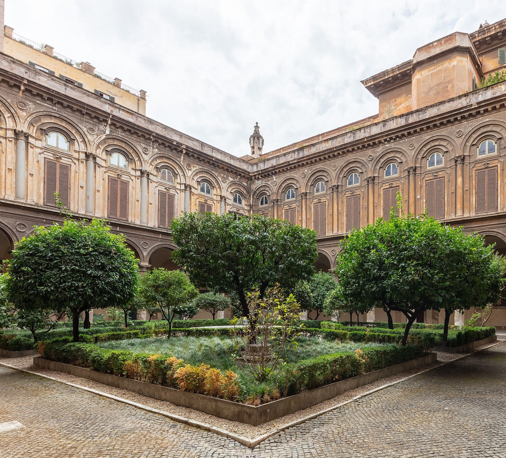A visitor's view entering Palazzo Doria Pamphilj, greeted by an elegant inner garden and the ornate facade of this hidden Roman palace.