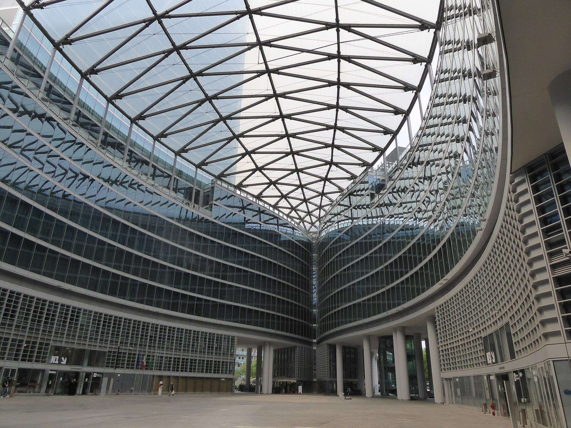 Vista della moderna facciata in vetro di Palazzo Lombardia e dell'ampia piazza aperta, con struttura angolare in acciaio del tetto, nel quartiere Porta Nuova di Milano.
