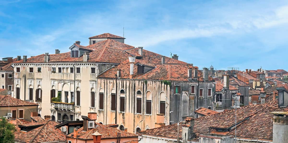 Blick auf das Museum Palazzo Mocenigo in Venedig mit klassischer gotischer Architektur und roten Ziegeldächern unter einem strahlend blauen Himmel.