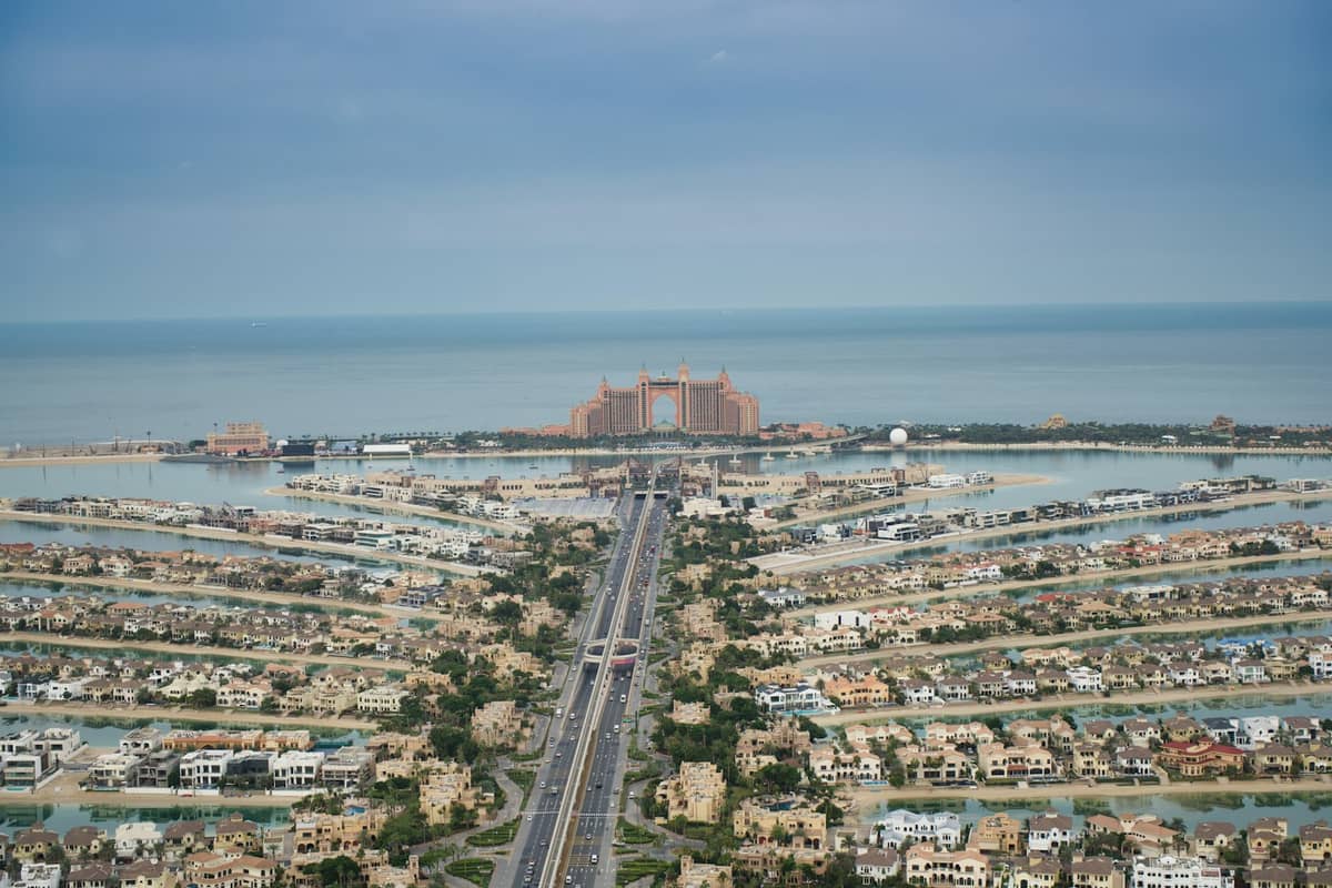 Luftaufnahme der Palm Jumeirah mit der palmenförmigen Insel, dem Stamm, den mit Villen gesäumten Wedeln und dem Atlantis Resort an der Spitze, umgeben vom blauen Meer.