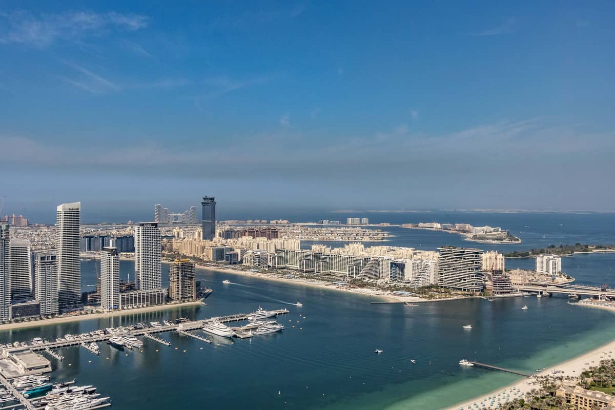 Luftaufnahme des Palm West Beach mit dem Sandstrand, modernen Gebäuden und dem türkisblauen Wasser entlang des westlichen Stamms des Palm Jumeirah in Dubai.