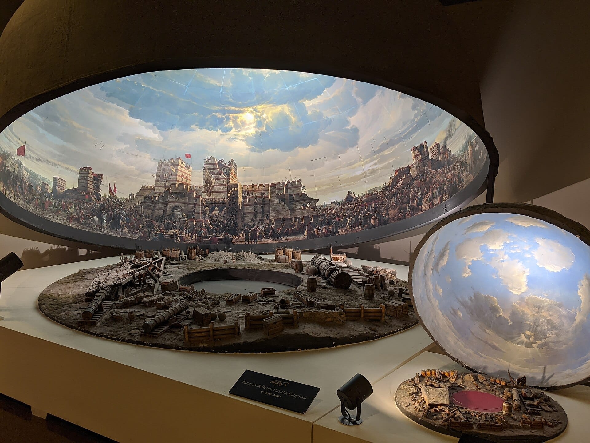 Modello dettagliato al Museo di Storia Panorama 1453 che mostra soldati ottomani, mura della città, cannoni e un drammatico sfondo di cielo sotto l'illuminazione del museo.
