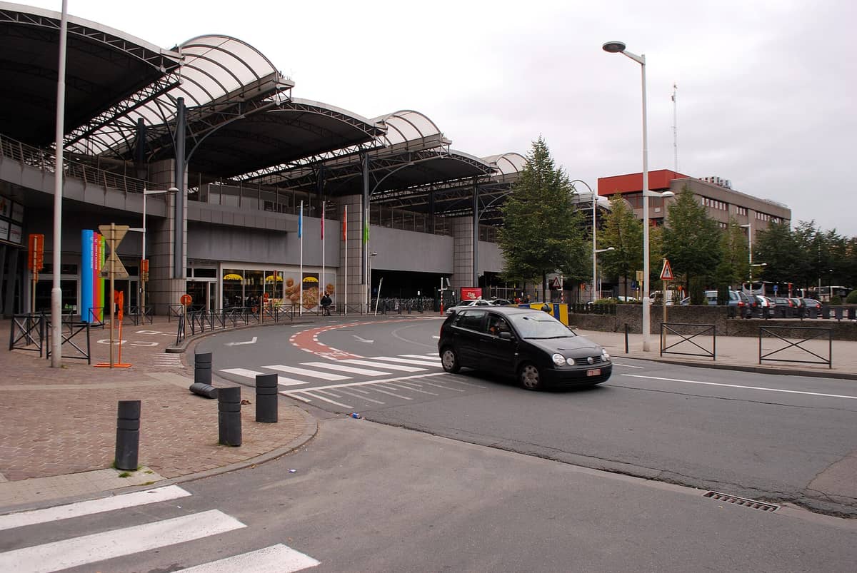 Vista exterior da estação ferroviária internacional Bruxelles-Midi/Brussel-Zuid em Bruxelas com arquitetura moderna e uma entrada curva.