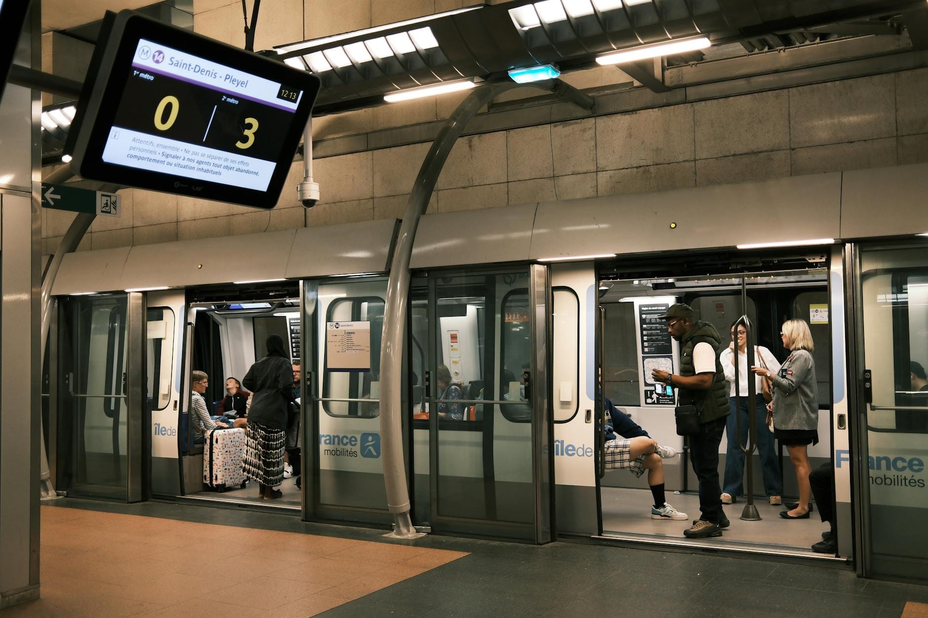 Persone che salgono e scendono da un moderno treno della Paris Métro in una stazione sotterranea ben illuminata, con famiglie e bambini visibili sulla banchina.