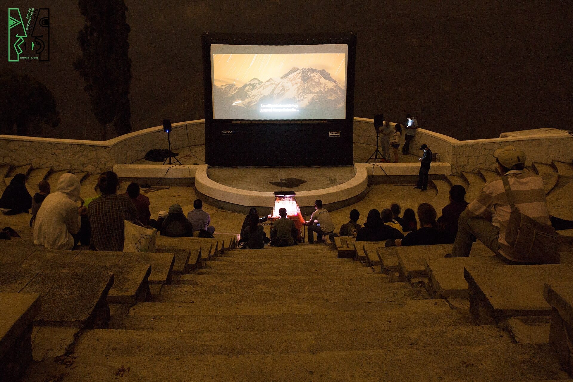 Anfiteatro all'aperto al Parque Mirador Independencia con persone che guardano una proiezione cinematografica notturna all'aperto, circondato da gradini in pietra e dall'oscurità del canyon.