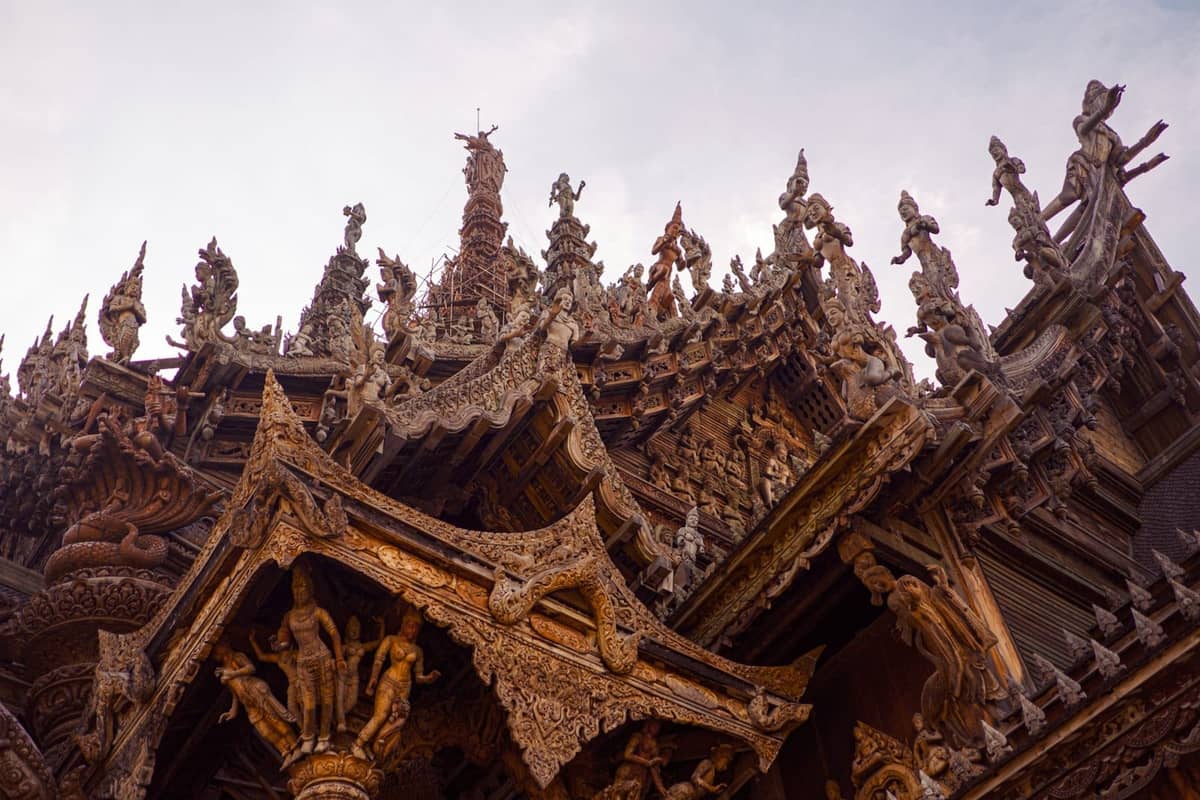 Ornate wooden carvings and pointed temple spires at the Sanctuary of Truth, a famous cultural landmark in Pattaya, Thailand