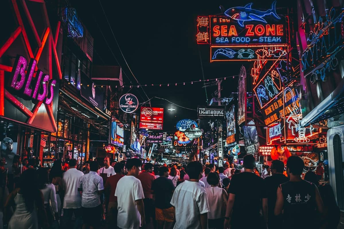 Crowded Walking Street at night in Pattaya, with vibrant neon signs, bustling crowds, and colorful nightlife venues.