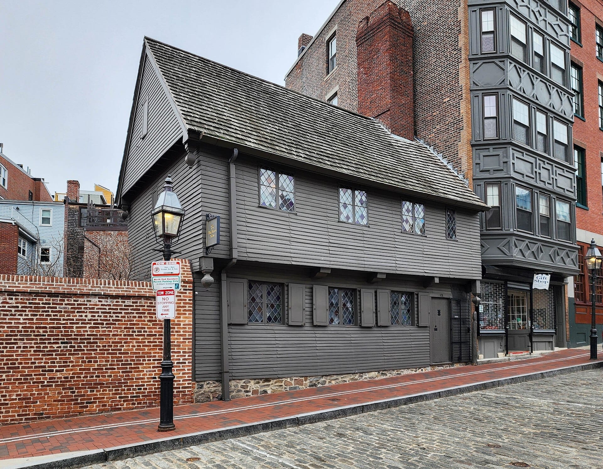 La Paul Revere House, un edificio coloniale in legno grigio con finestre a vetri a forma di diamante, si trova su una strada acciottolata nel quartiere North End di Boston.