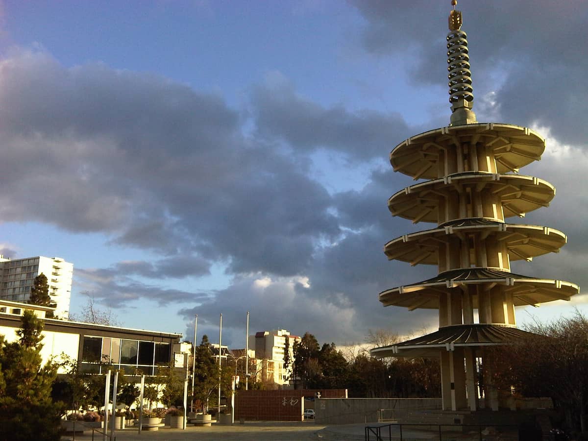 La Pagoda de la Paz de cinco niveles en Japantown, San Francisco, con un dramático cielo nublado al fondo, la plaza y el paisaje urbano circundante.