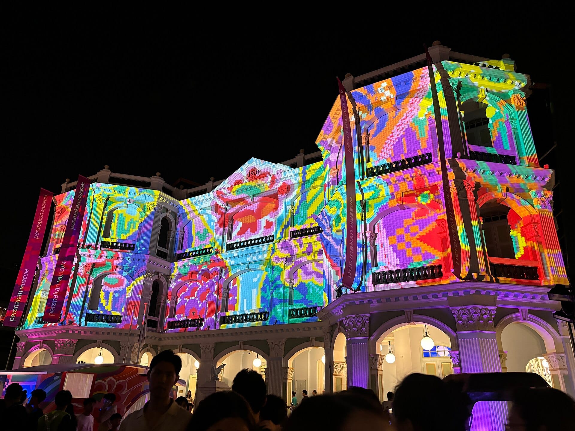 อาคาร Peranakan Museum ในสิงคโปร์ที่ได้รับแสงไฟสว่างในยามค่ำคืนด้วยการฉายแสงสีสันสดใสบนด้านหน้าอาคารสมัยอาณานิคม