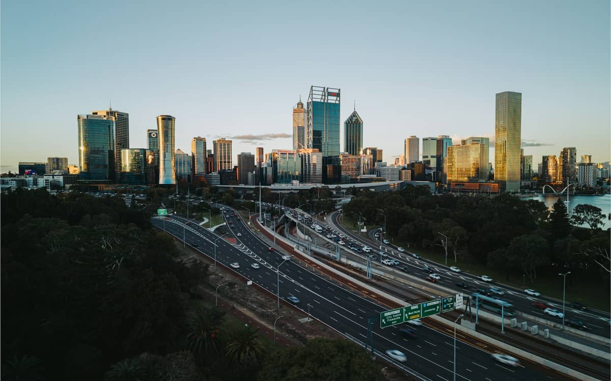Aerial view of the Perth city skyline with major highways leading towards the central business district at sunset.