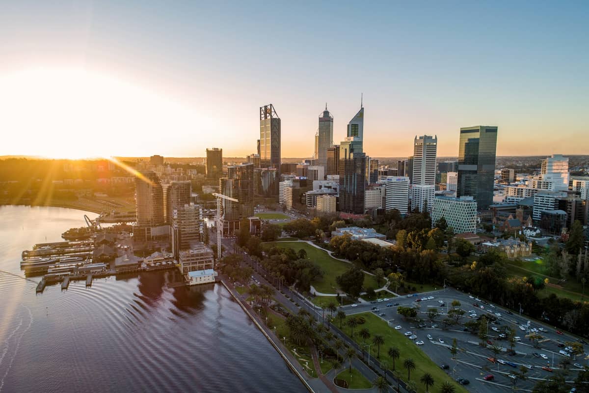 วิวมุมสูงย่าน Perth CBD ยามพระอาทิตย์ขึ้น เห็นริมฝั่งแม่น้ำ Swan และตึกระฟ้าเหนือสวนสาธารณะ