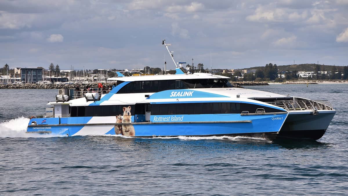 Fähre nach Rottnest Island namens Sealink Quokka 1 fährt vom Hafen Fremantle ab, mit Gebäuden und Marina im Hintergrund.
