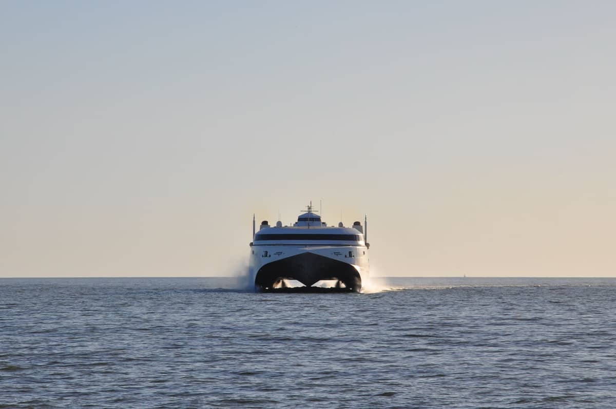 Eine moderne Katamaran-Fähre nähert sich auf offenem Wasser unter klarem Himmel und repräsentiert wahrscheinlich einen Premium-Fährdienst in der Nähe von Perth.