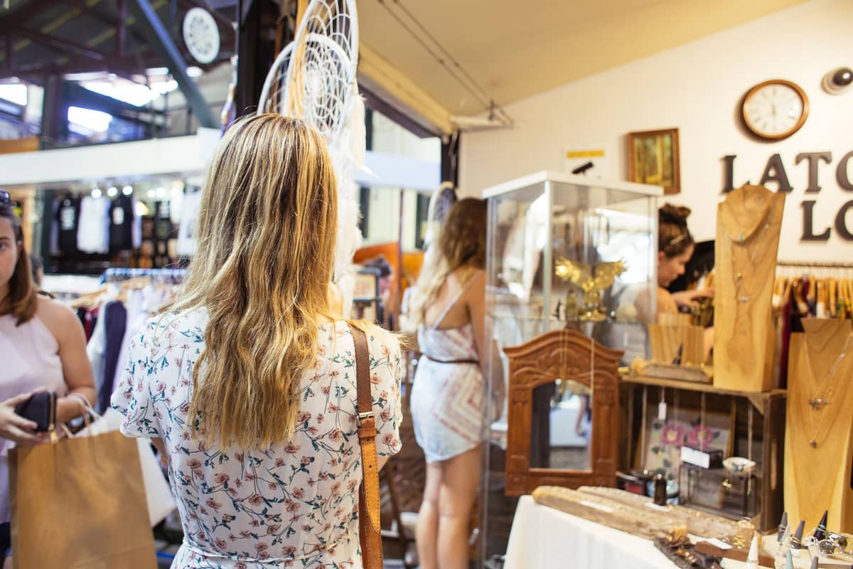 Ludzie oglądający ręcznie robione wyroby i vintage'owe przedmioty na straganach wewnątrz Fremantle Markets w Perth, Australia Zachodnia. Atmosfera jest żywa i autentyczna.