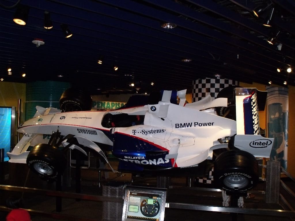 A full-sized Formula 1 racing car exhibit with BMW Power logos on display under spotlights inside Petrosains Discovery Centre at KLCC.