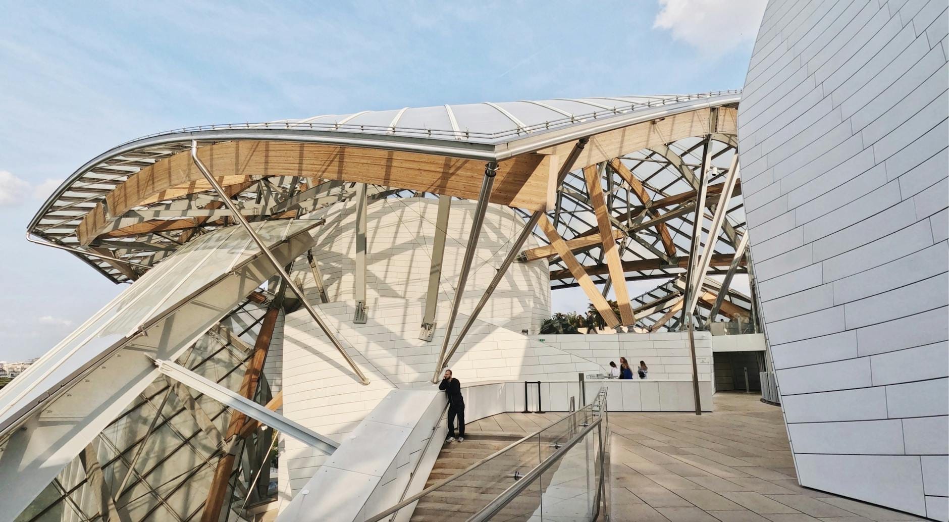 Vista ampia dell'edificio moderno della Philharmonie de Paris, con le sue curve di vetro e metallo, che mostrano l'architettura audace e i visitatori sulla terrazza.