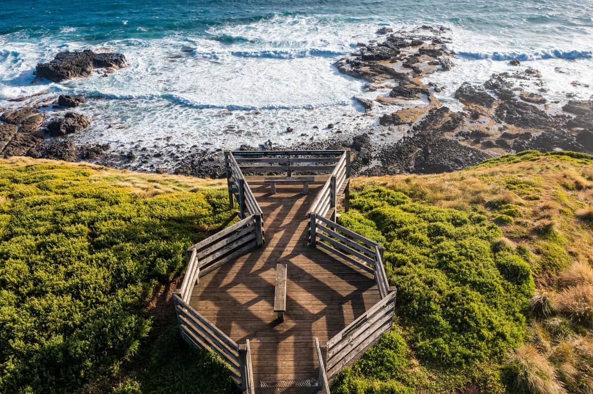Una amplia plataforma de madera al borde de Phillip Island con vistas a la costa rocosa y al océano azul donde tiene lugar el Desfile de Pingüinos.