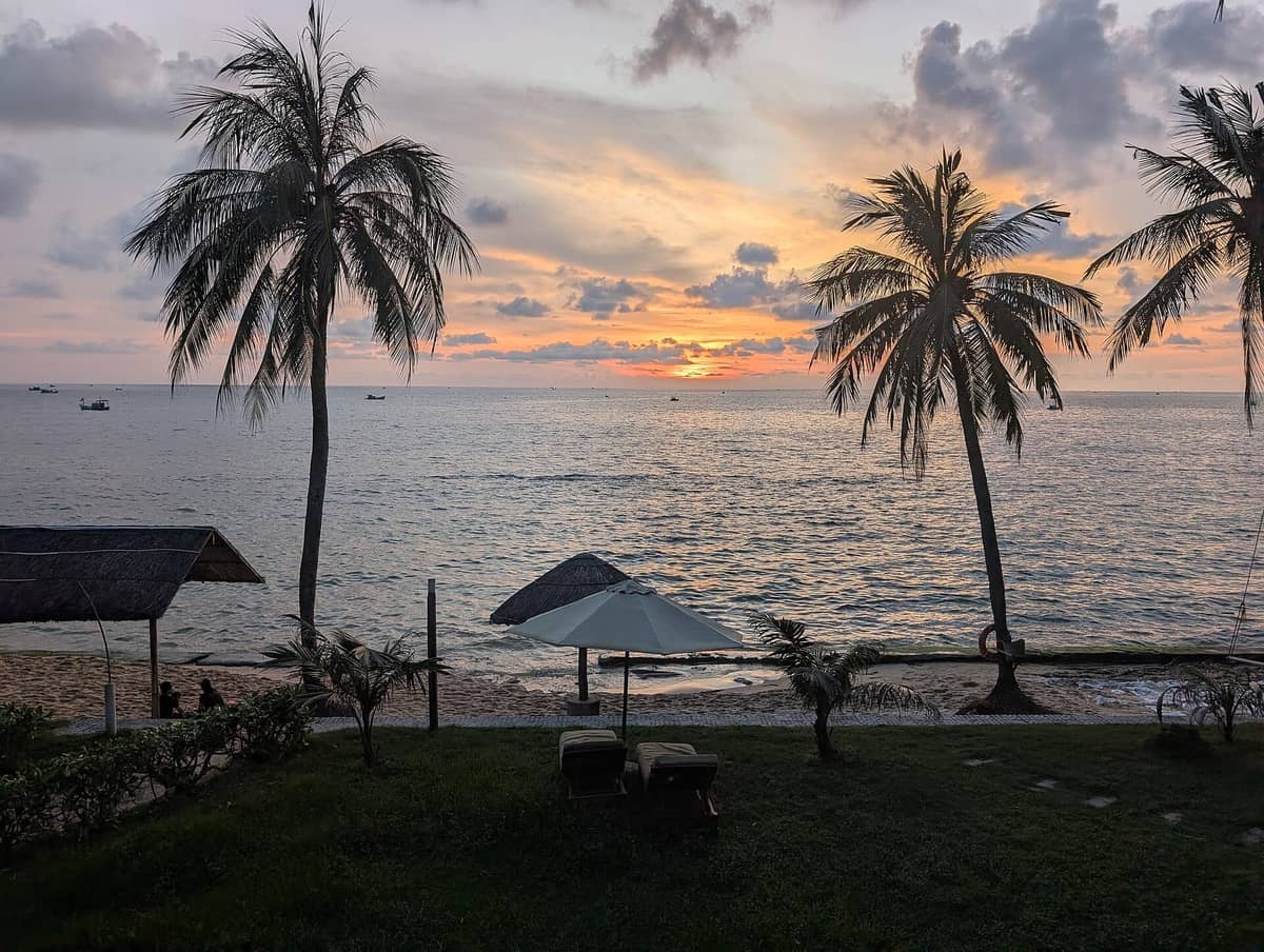 Phu Quoc beach at sunset with palm trees, calm sea, and relaxed resort setting