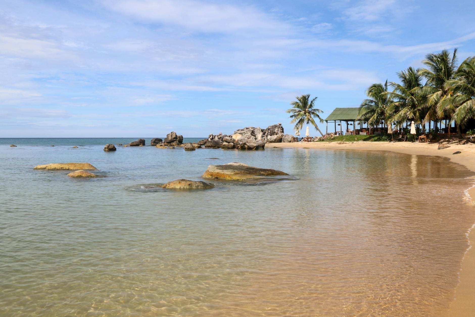 Ruhige, flache Bucht mit klarem Wasser, Felsen und Palmen entlang eines Sandstrandes, typische Einstiegsbedingungen zum Schnorcheln auf Phu Quoc.