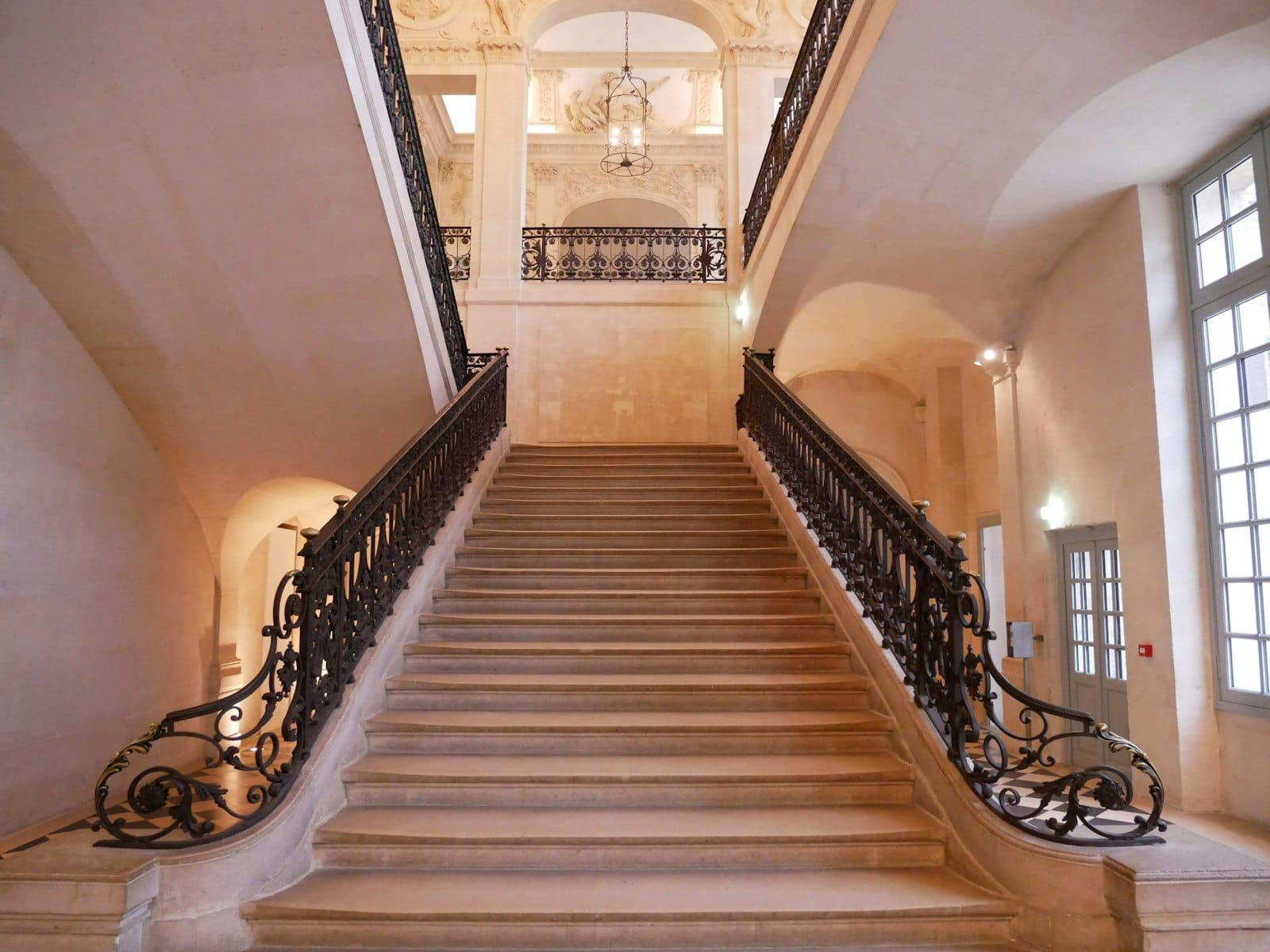 Elegante scalinata in pietra con ringhiere in ferro battuto all'interno dello storico Hôtel Salé, sede del Musée Picasso di Parigi, illuminata dalla luce naturale.