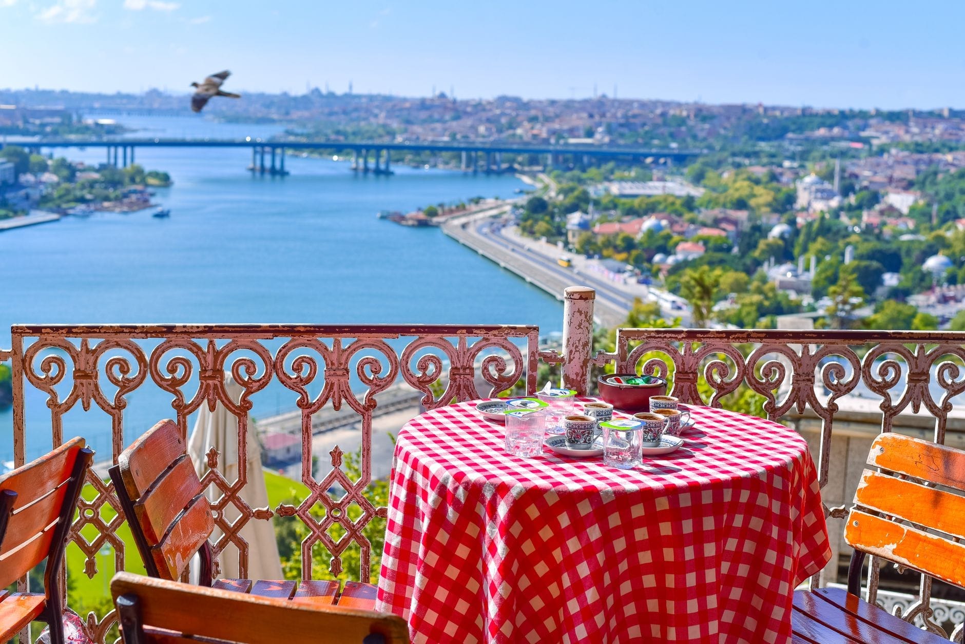 Tavolo con tovaglia a quadri rossi apparecchiato per il tè al Caffè Pierre Loti, con vista sul Corno d'Oro e sul panorama di Istanbul in una giornata serena.