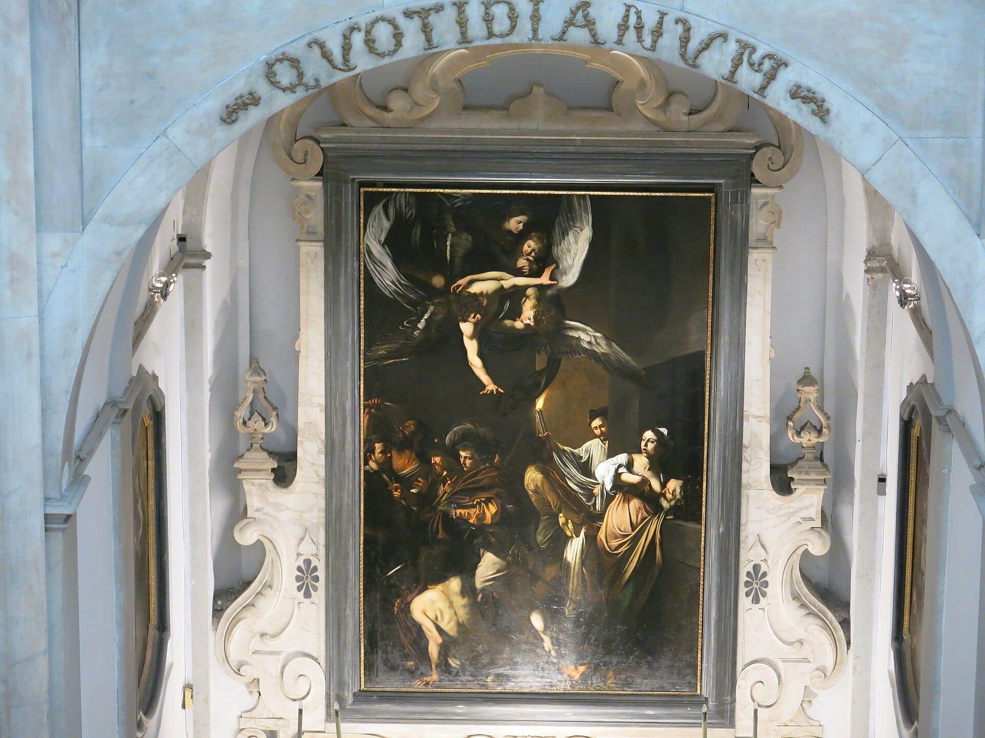 Le Sette opere di Misericordia di Caravaggio esposte in un altare con cornice in marmo al Pio Monte della Misericordia, Napoli, sotto luce naturale.