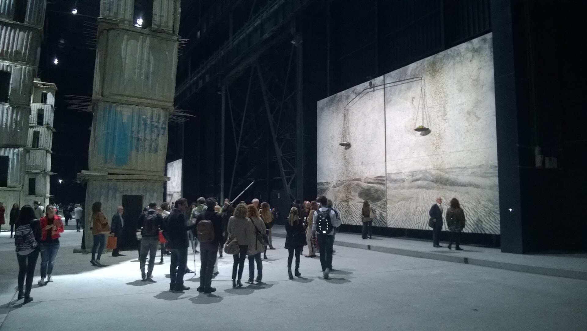 I visitatori esplorano grandi installazioni d'arte contemporanea nell'ampio spazio industriale del Pirelli HangarBicocca a Milano, con strutture imponenti e opere d'arte delle dimensioni di una parete.