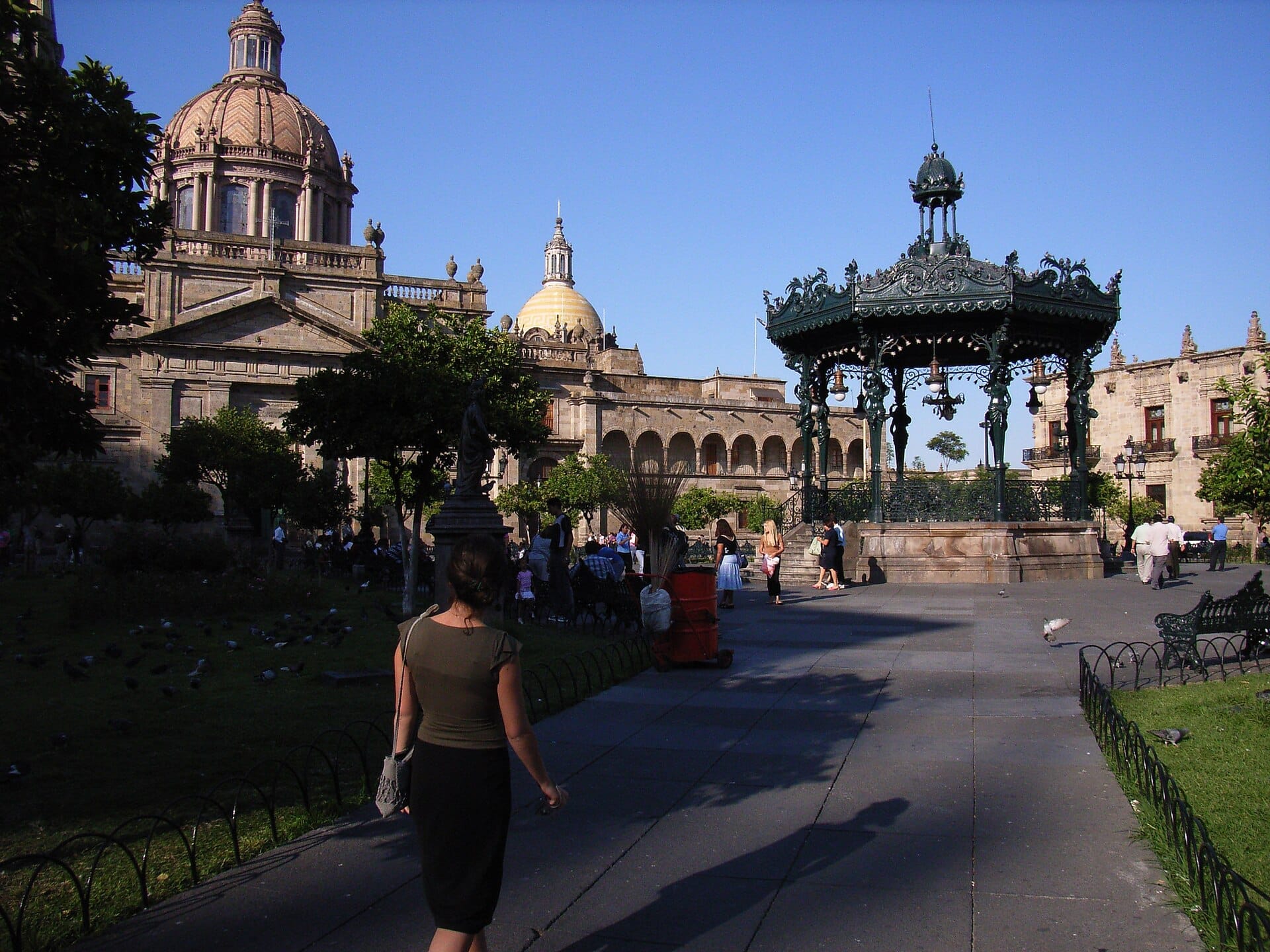 Plaza de Armas Guadalajara con il suo ornato chiosco della musica art nouveau francese, le cupole della cattedrale, il verde circostante e persone che godono di un pomeriggio soleggiato.