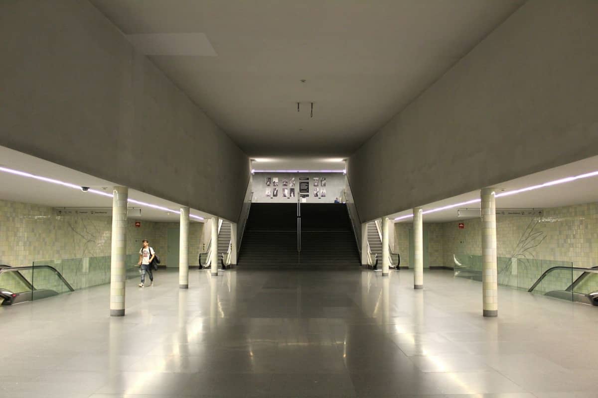 Wnętrze nowoczesnego terminalu transportowego w Porto z ruchomymi schodami, schodami i wyraźnym oznakowaniem, typowe dla stref przyjazdów.