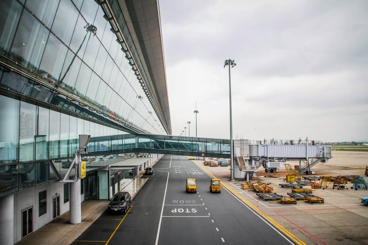 Nowoczesny terminal lotniska Porto z przeszkloną fasadą, rękawami lotniczymi i pojazdami lotniskowymi w pochmurny dzień.
