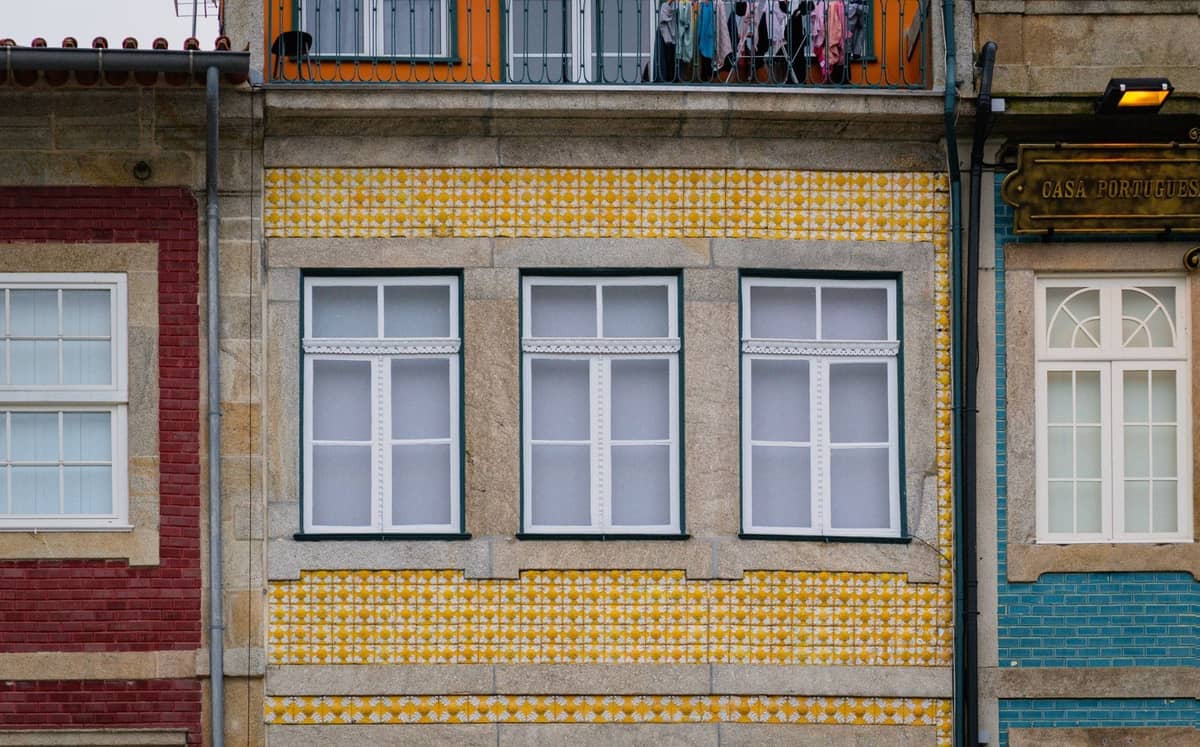 Straßenansicht traditioneller Wohngebäude in Porto mit bunten Azulejo-Kachelfassaden in Gelb, Rot und Blau.