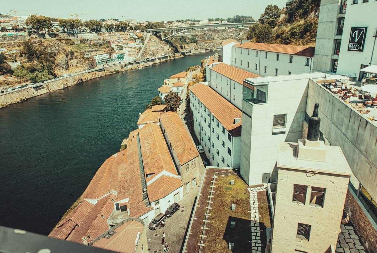 Luftaufnahme der Portweinkeller am Flussufer von Vila Nova de Gaia mit dem Fluss Douro und einer entfernten Brücke in Porto, Portugal.