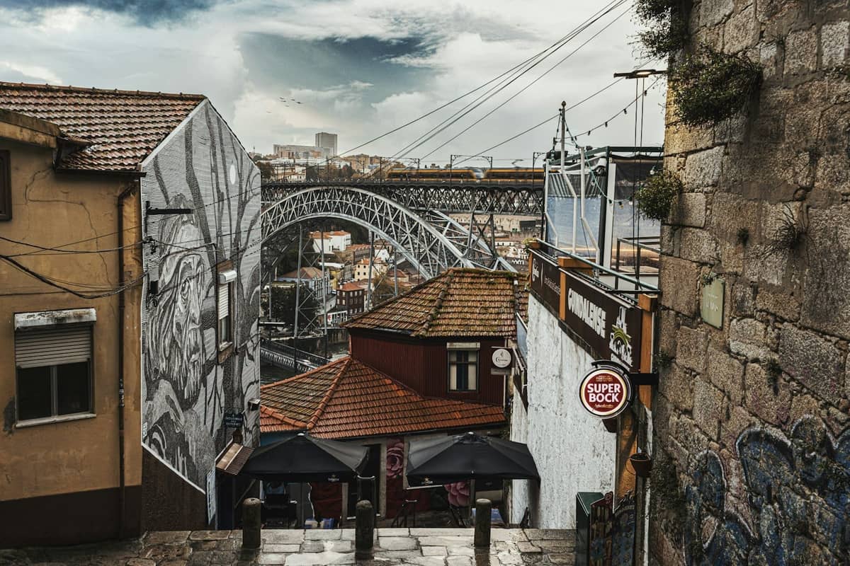 Blick die Steinstufen hinunter zur Brücke Dom Luís I, mit historischen Gebäuden und Street-Art im Ribeira-Viertel von Porto.
