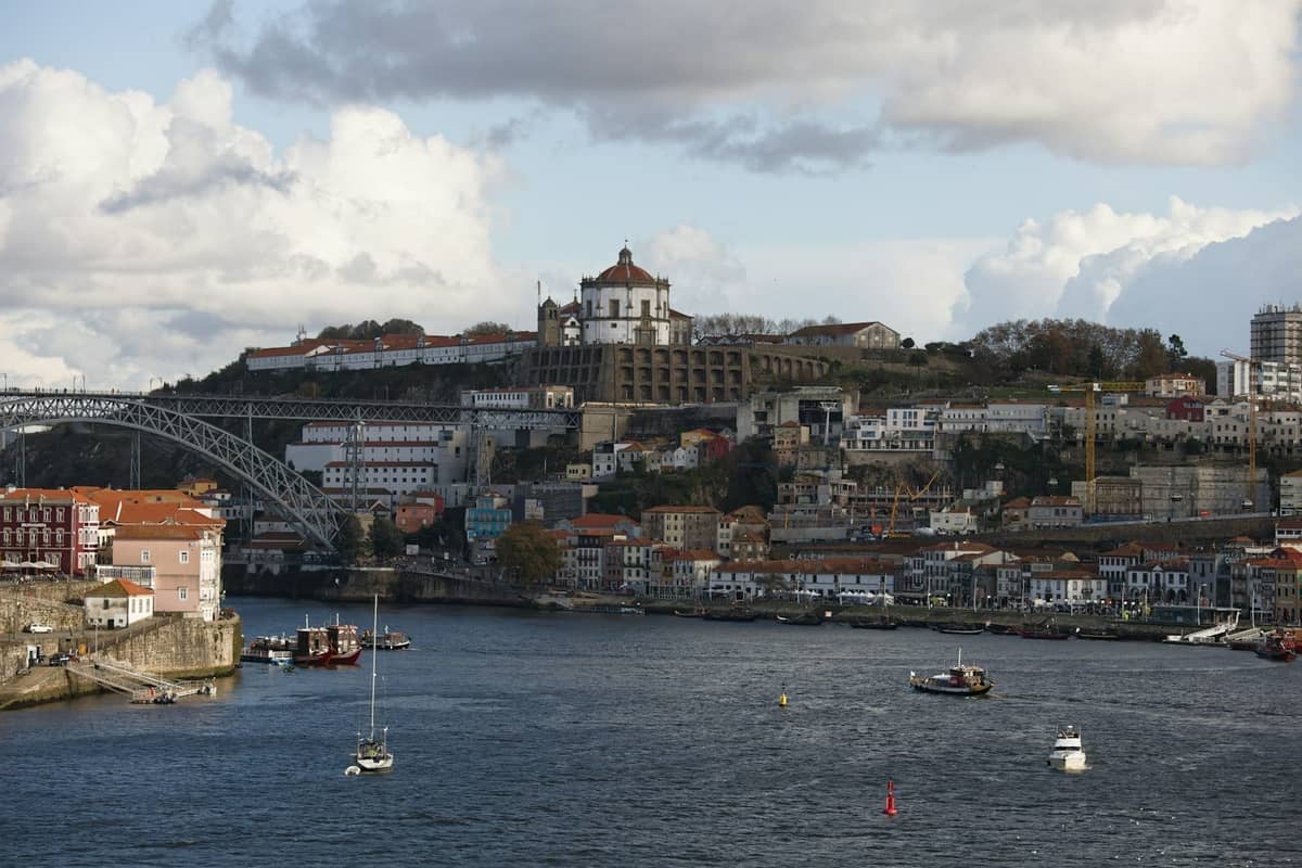 Panorama de Porto de l'autre côté du fleuve Douro avec le Monastère de Serra do Pilar au sommet de la colline et des bateaux sur l'eau.