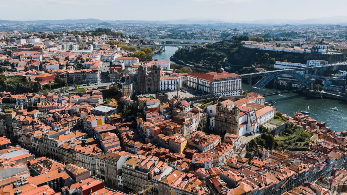 Vista aerea panoramica di Porto con edifici storici, il fiume Douro e l'iconico ponte in una giornata limpida.
