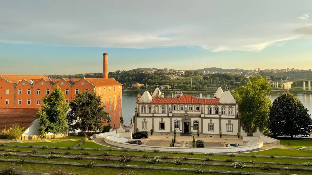 Elegante edificio di villa bianca con tetto in terracotta che si affaccia sul fiume Douro a Porto, immerso nei giardini e adiacente a una cantina di vino Porto.