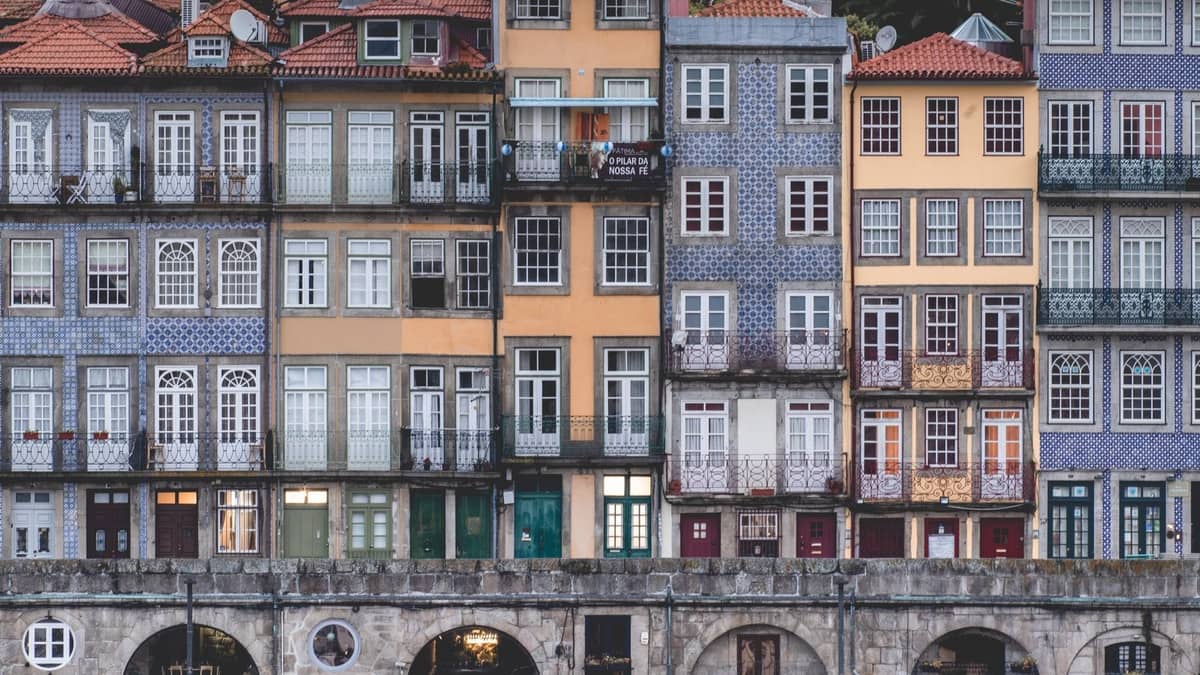 Facciate storiche colorate con pareti piastrellate e balconi a Porto, Portogallo, fotografate frontalmente, che evidenziano il carattere unico e i dettagli architettonici.